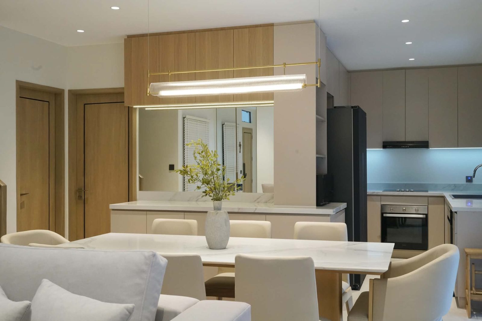 Open-plan kitchen and dining area with oak upper cabinets and a mirrored splash